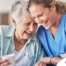 A woman in scrubs laughs with a senior woman, representing how caregiving can be a great career choice.